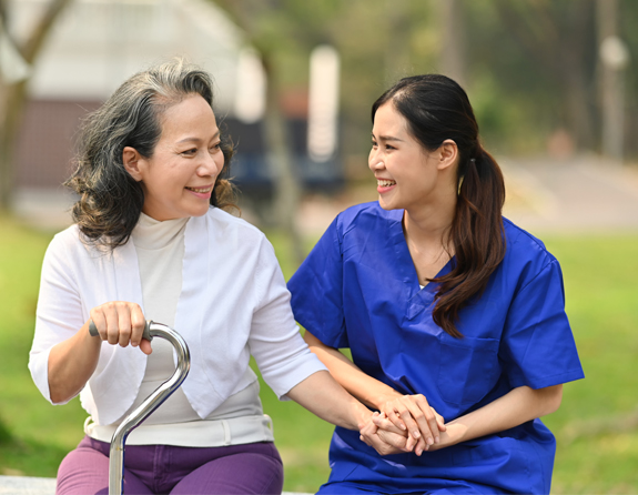 caregiver smiling while holding the hands of a woman